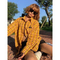 A loose-fit yellow plaid cardigan shirt for men and women, shown on a hanger.