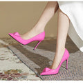 Pink patent leather women's stiletto heels with pointed toe, rivet buckle, and low-cut vamp on a white background.