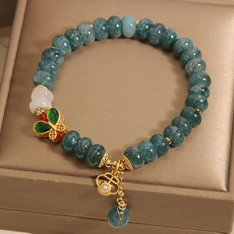 Blue water jade bead bracelet with white agate abacus beads and a butterfly charm.