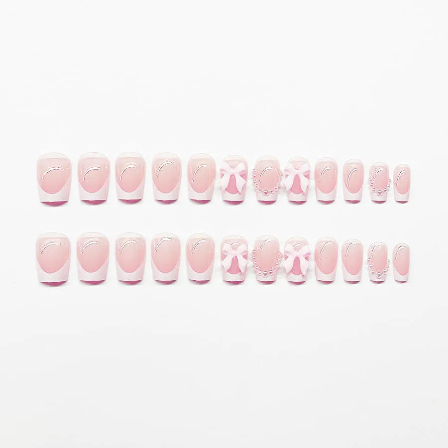 Set of short square press-on nails with white French tips, bow patterns, and tulip designs next to S274 glue bottles.