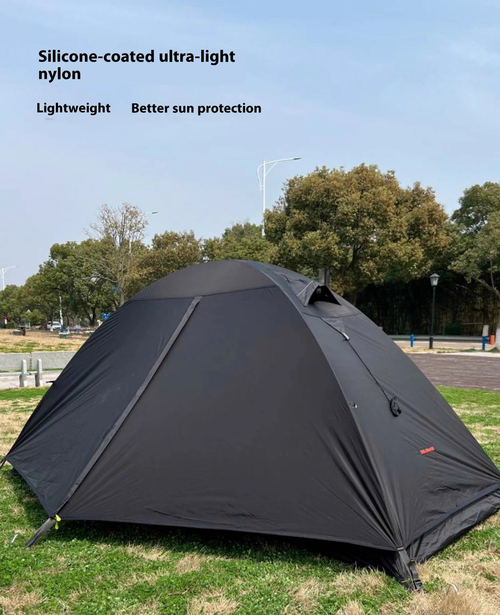Red single person backpacking tent with aluminium poles pitched in a forest, showing double-layer design and vestibule.