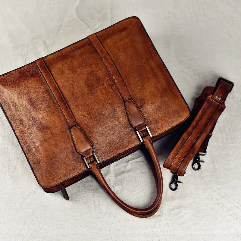 Men's brown leather horizontal business handbag with zipper, shown next to a 14-inch laptop for scale.