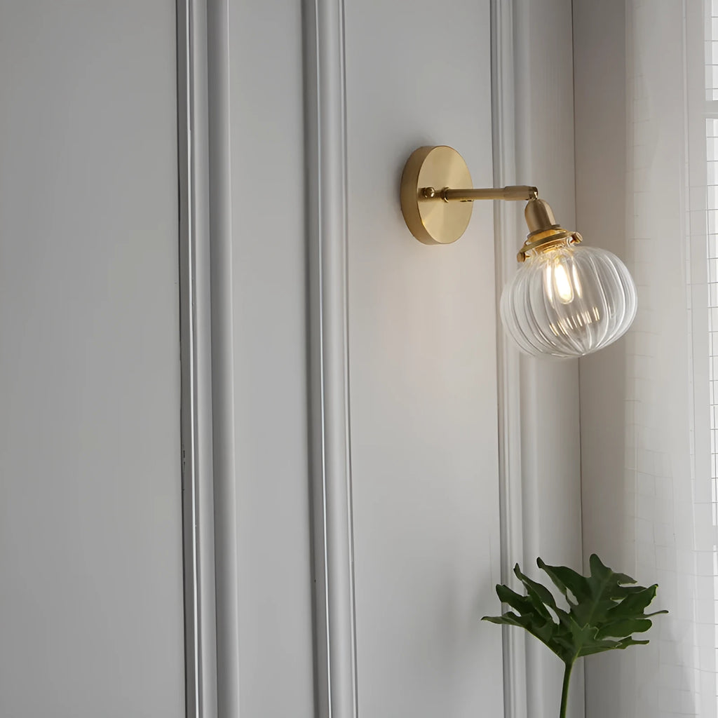 Close-up of a hand-blown pumpkin-shaped glass wall lamp in blue, mounted on a beige wall.