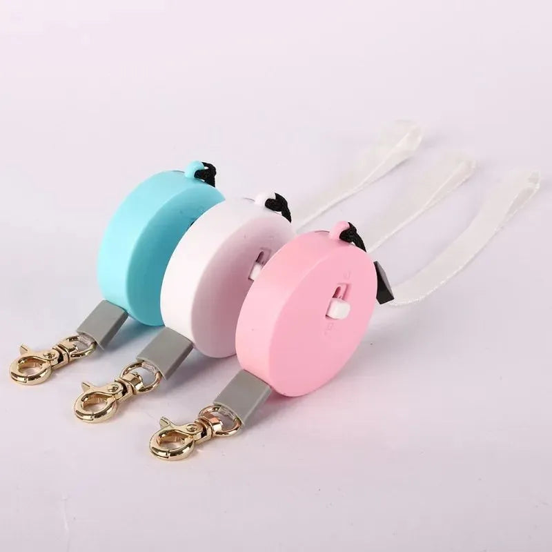 Retractable dog lead with 2m nylon tape, lock button, and non-slip handle in white, pink, or blue.