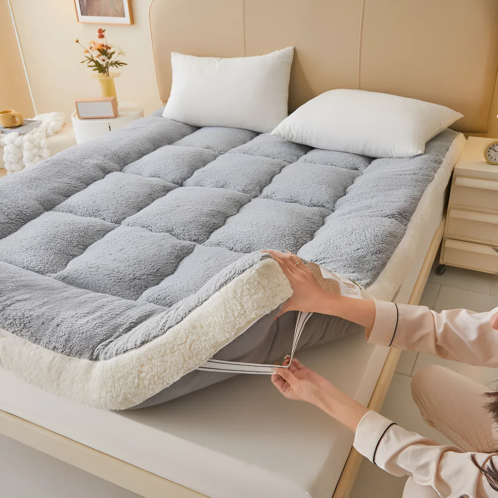 Lambswool mattress cushion with velvet cover in grey and white edge, on a bed