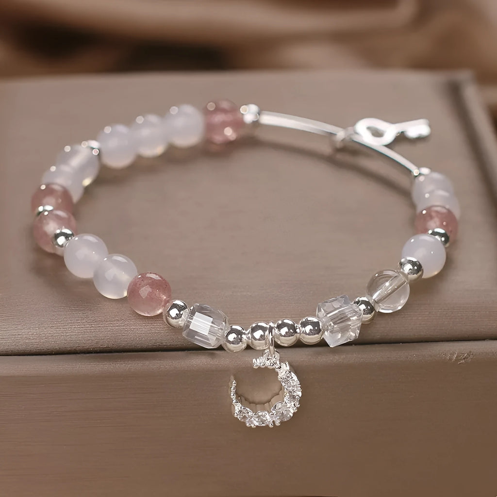 Natural strawberry quartz bracelet with pink cube sugar beads and moon pendant on a flat surface