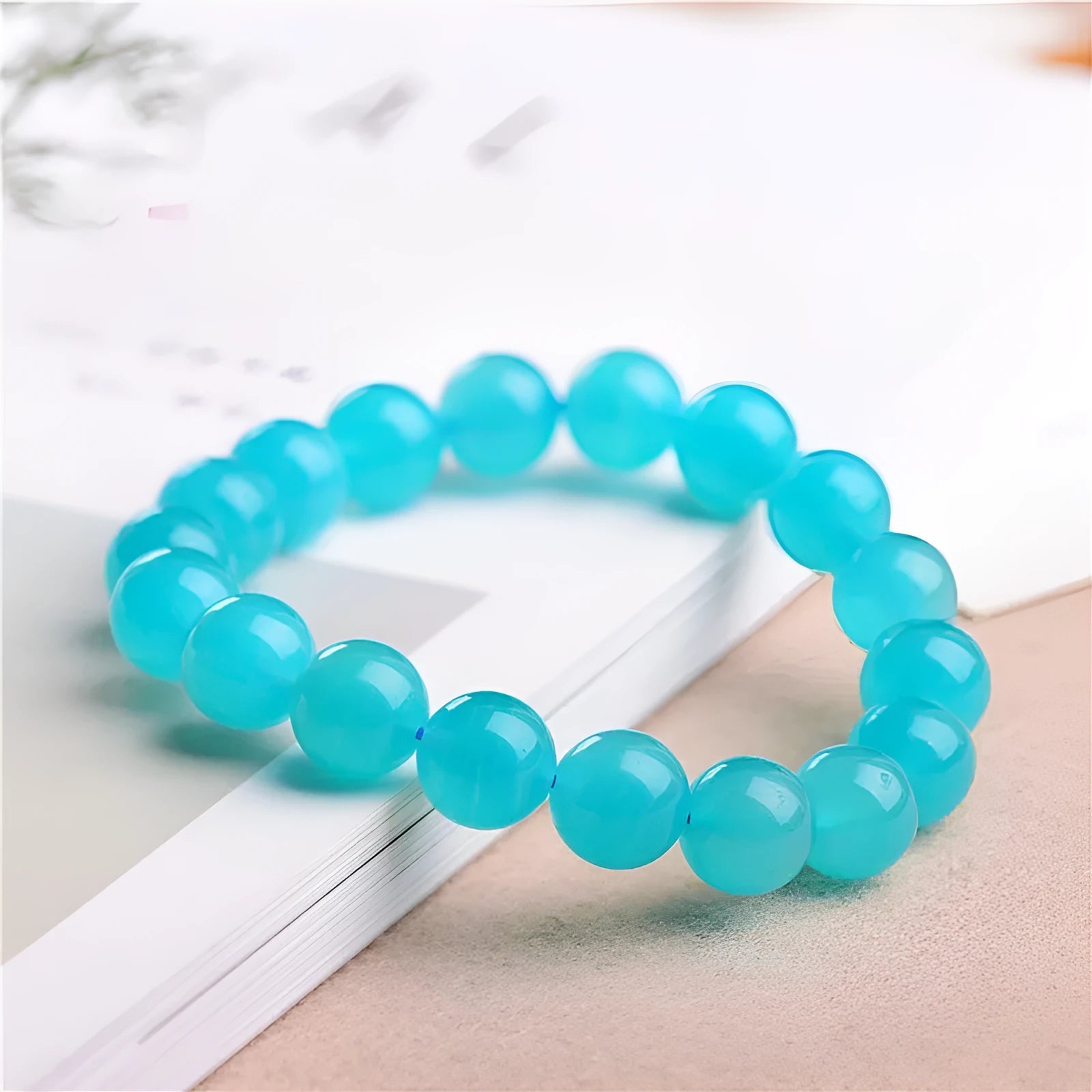Loose natural Amazonite beads in ice blue colour, showing polished surfaces and irregular scattered shapes next to a finished bracelet.
