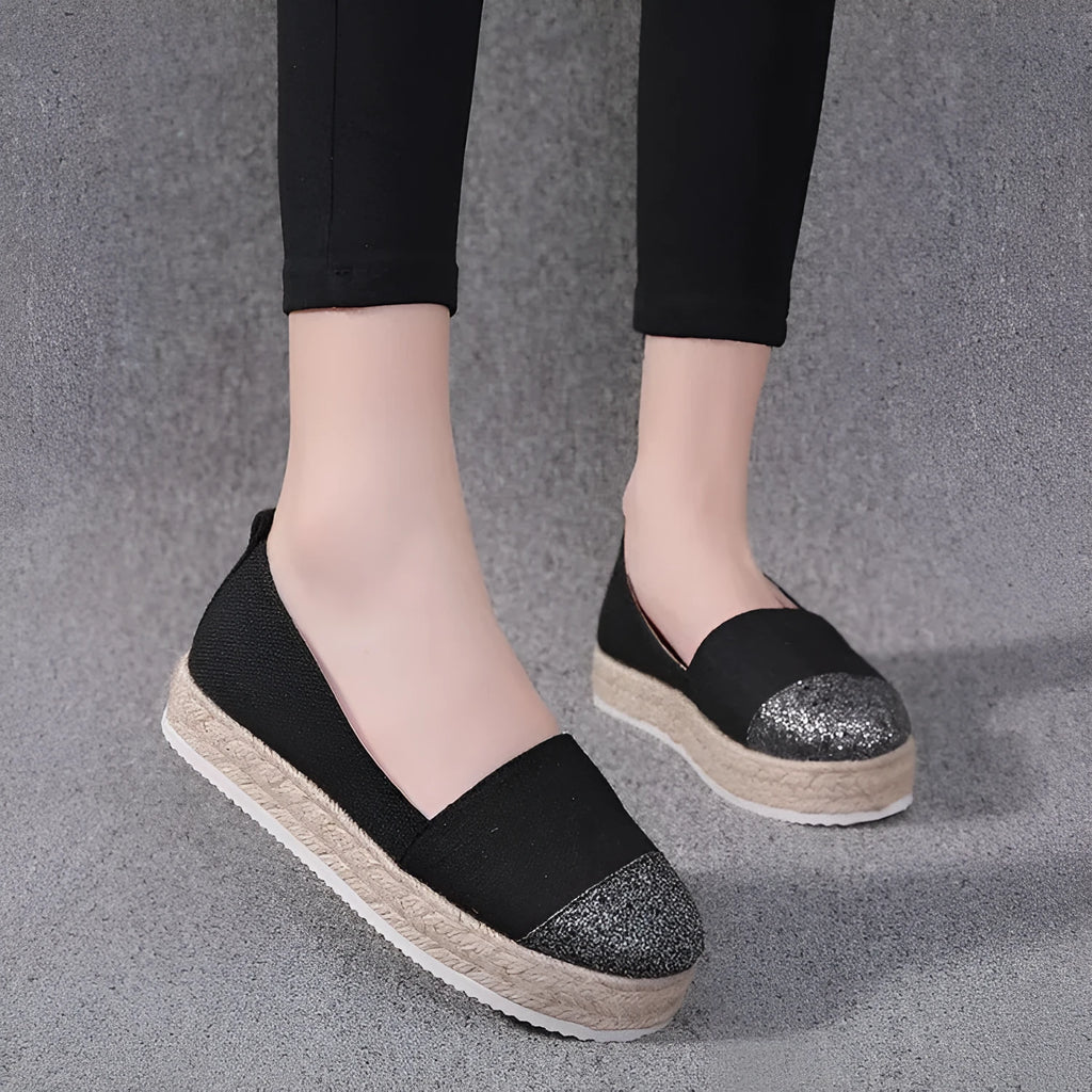 Beige and black women's canvas flat shoes with round toe and slip-on design.