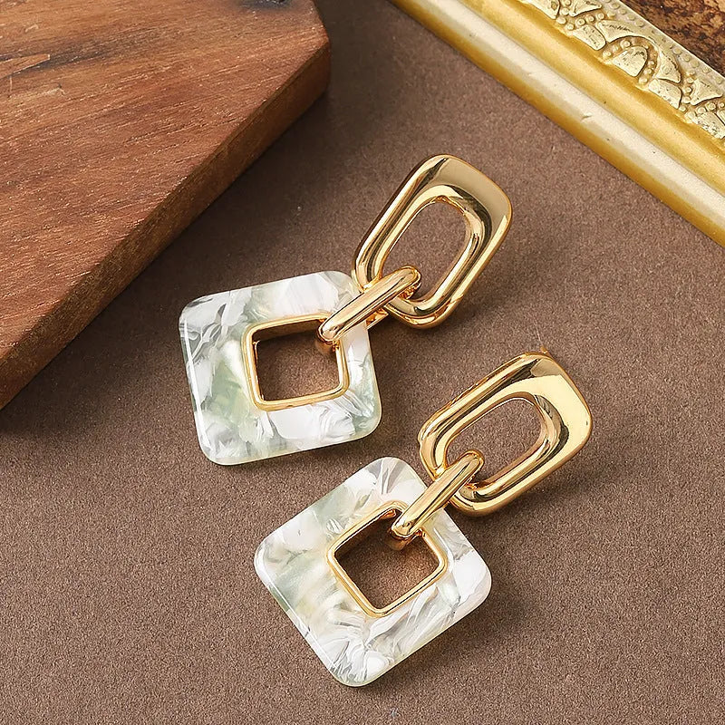 A pair of hollow geometric square copper earrings with chamfered corners on a white background.