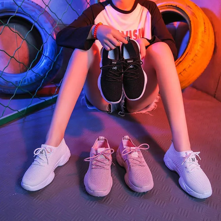 Women's low-top white sport shoes with thick rubber sole and woven upper, showing front strap closure.