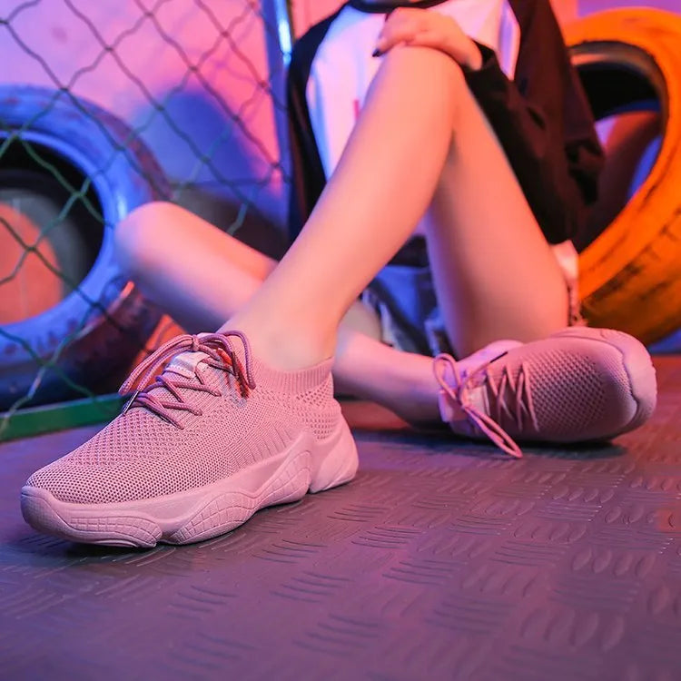 Women's low-top white sport shoes with thick rubber sole and woven upper, showing front strap closure.
