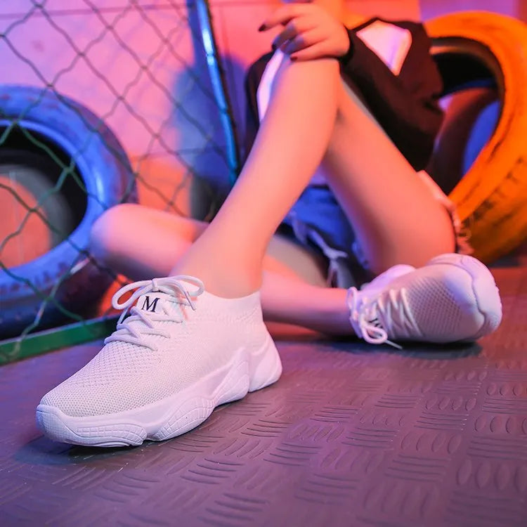Women's low-top white sport shoes with thick rubber sole and woven upper, showing front strap closure.