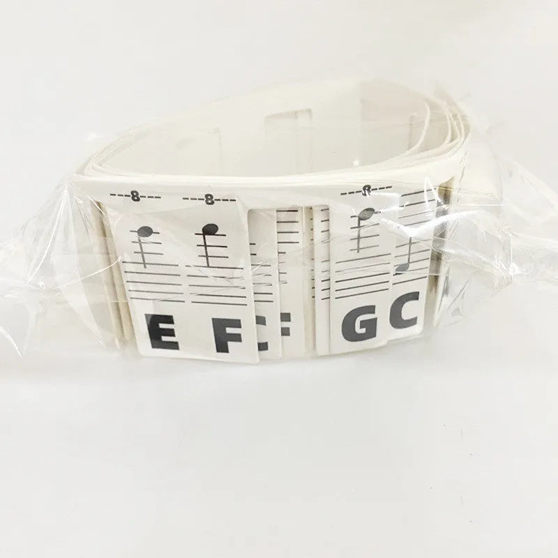 White cardboard piano keyboard stickers showing staff notation for 88 keys with separate bags for colour and black notes