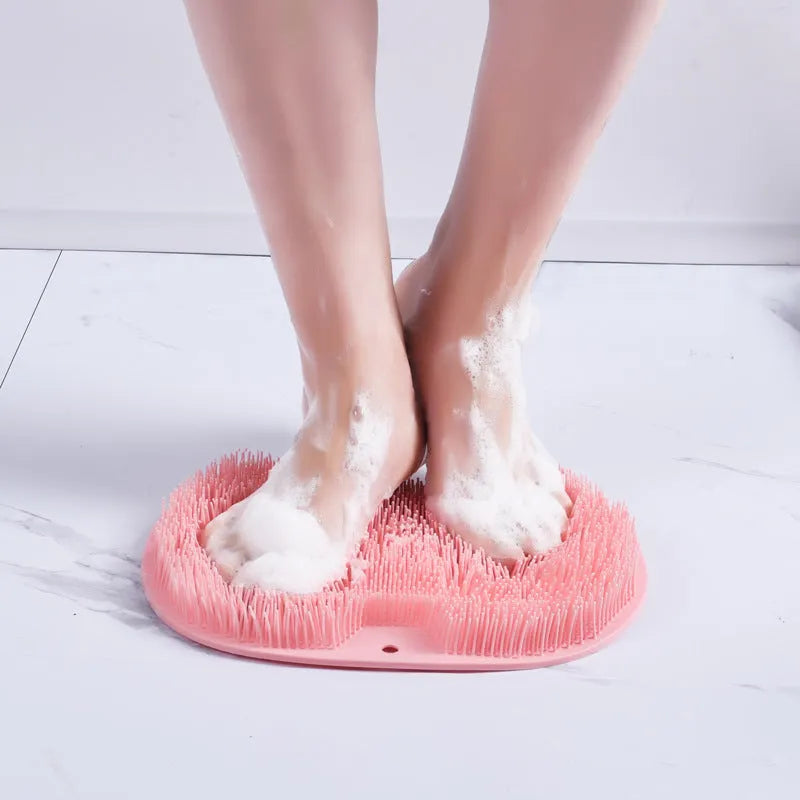Orange non-slip bath brush with silicone bristles and suction cups on a bathroom floor.