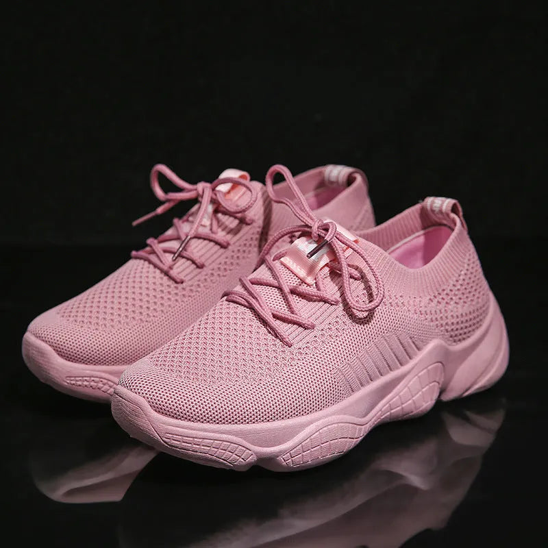 Women's low-top white sport shoes with thick rubber sole and woven upper, showing front strap closure.