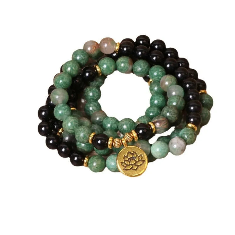 Green and black alloy beads on an elasticated bracelet, shown on a wrist.