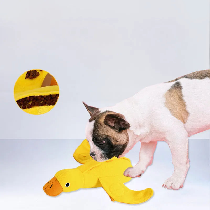 Yellow plush duck dog training toy with a squeaker and treat compartments on a white background.