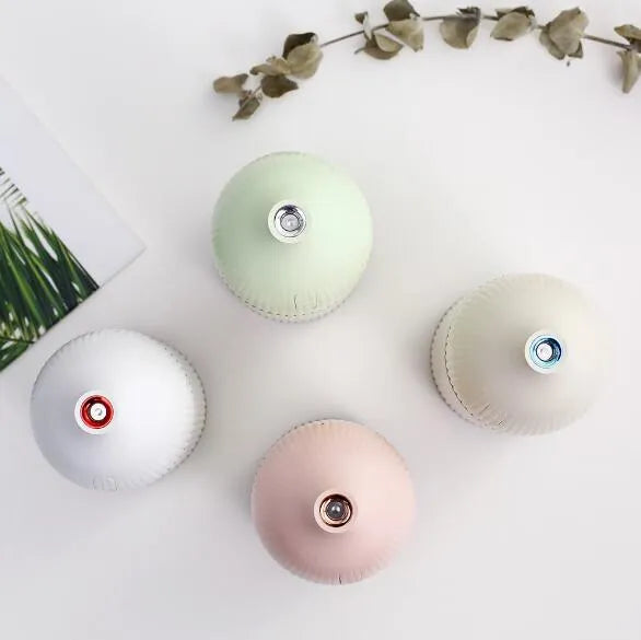 White USB aromatherapy diffuser and humidifier with LED light on a wooden desk