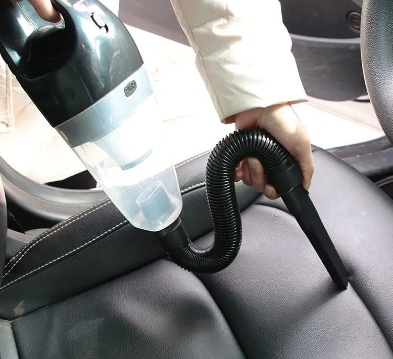 Orange 12V portable handheld car vacuum cleaner with nozzle attachments on a car seat.