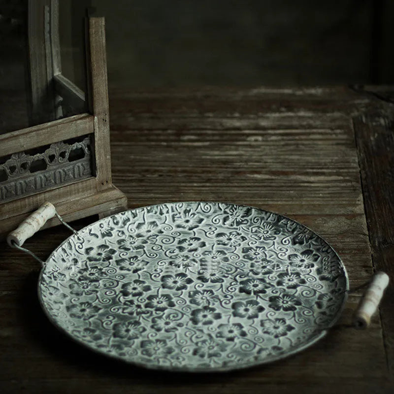 Round wrought iron belt storage tray set in two sizes on a wooden table.