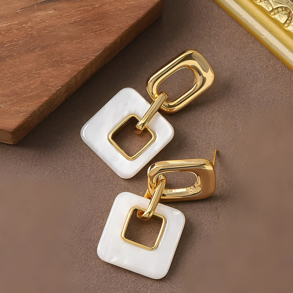 A pair of hollow geometric square copper earrings with chamfered corners on a white background.