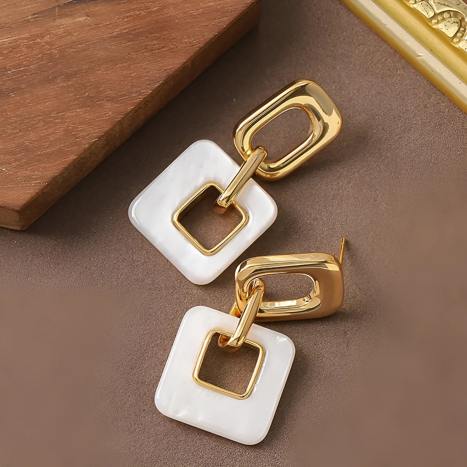 A pair of hollow geometric square copper earrings with chamfered corners on a white background.