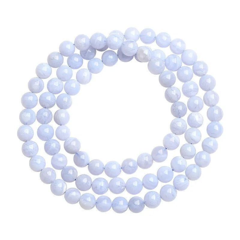 Close-up of a handmade blue agate bracelet with natural striped beads on a wrist.