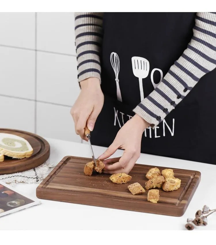Solid black walnut wood chopping board with juice groove, available in round or rectangular sizes.