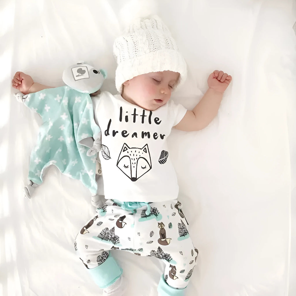 Newborn baby clothes set with white cotton T-shirt and grey pants on a soft background