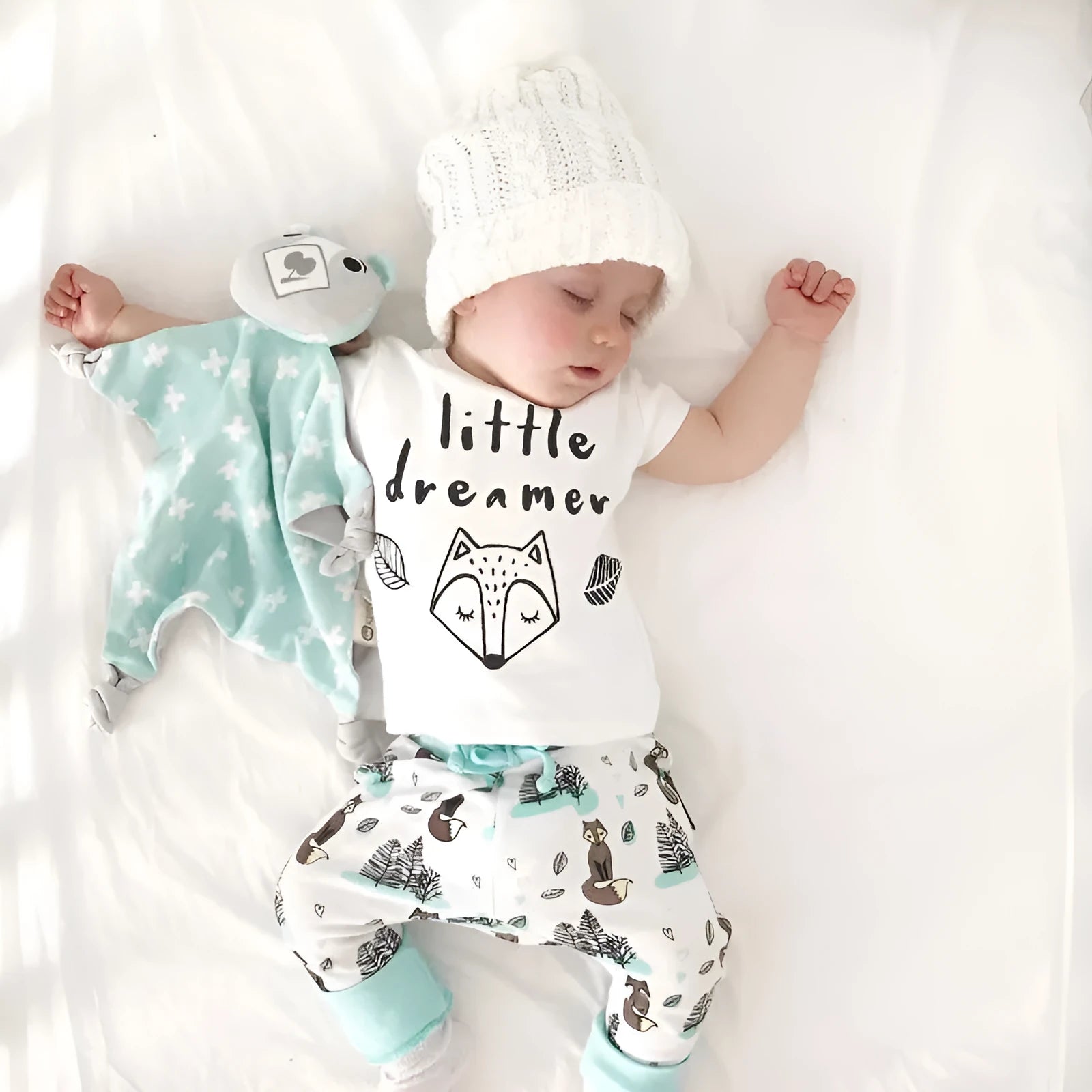 Newborn baby clothes set with white cotton T-shirt and grey pants on a soft background