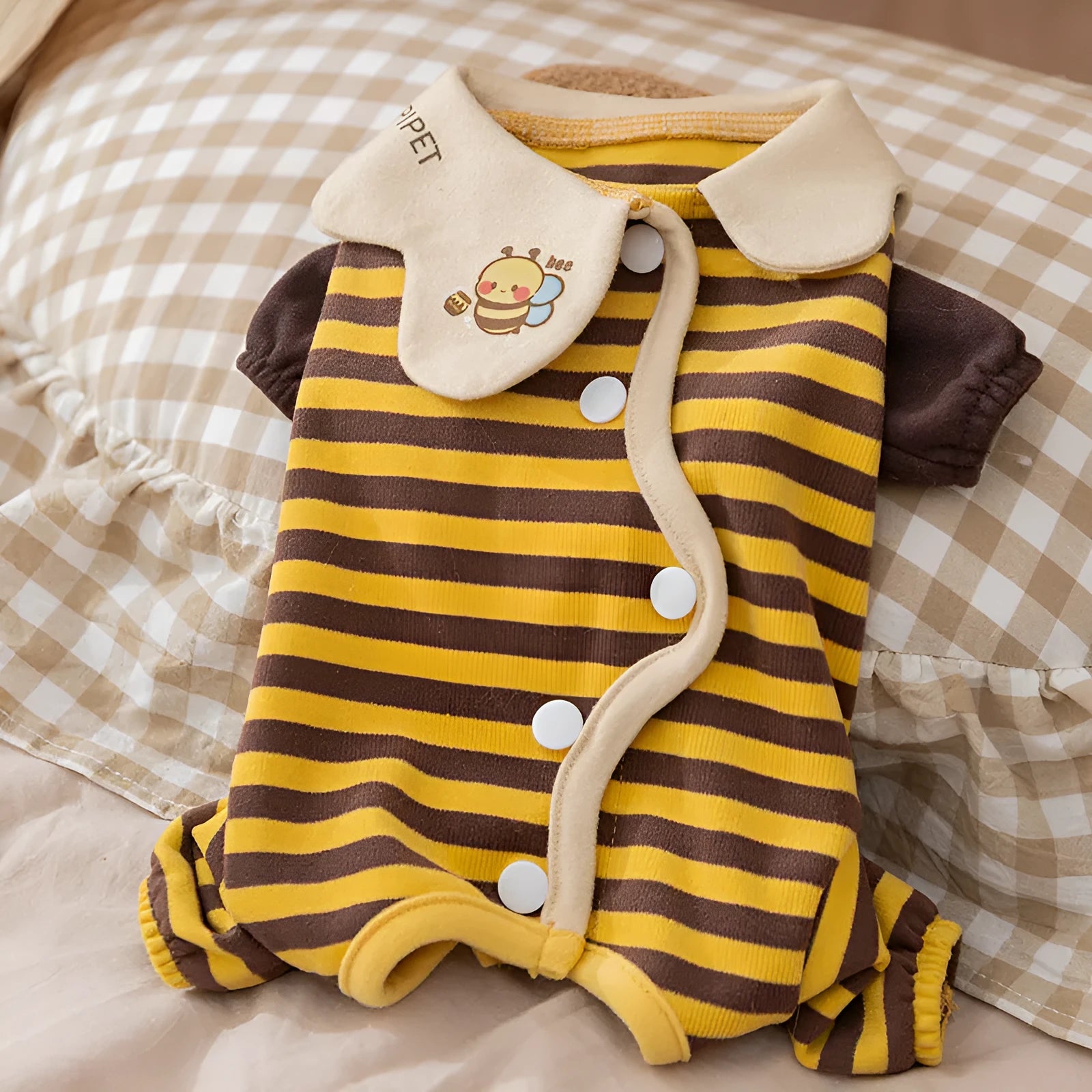 Yellow dog pajamas with bee pattern and lapel on small dog standing indoors