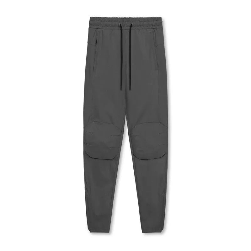 Man wearing dark grey loose-fit fitness trousers with tied ankles, made of quick-dry polyester blend fabric.