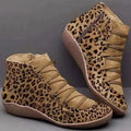 Women's flat casual booties in leopard print with round toe and wedge heel on a wooden floor.