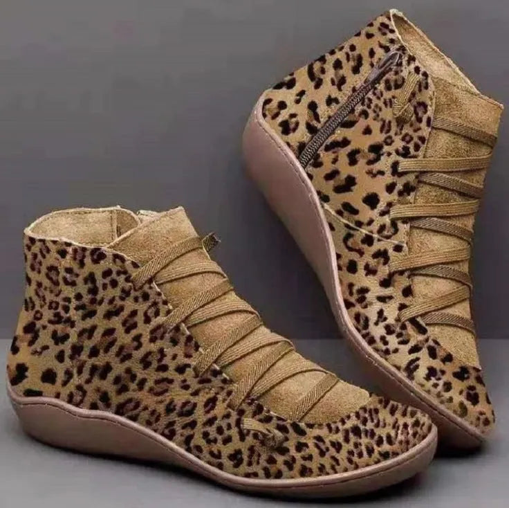 Women's flat casual booties in leopard print with round toe and wedge heel on a wooden floor.