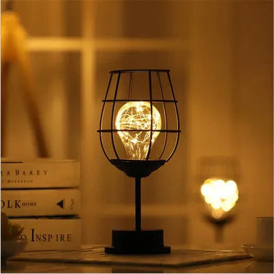 Minimalist hollow wrought iron table lamp in red wine bottle design with warm white LED light.