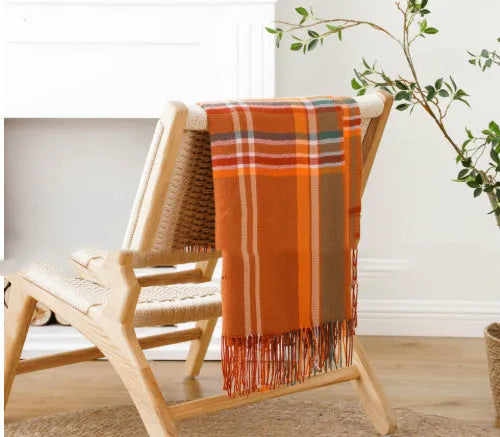 Acrylic chenille plaid throw blanket with tassel trim in gray and white geometric pattern on sofa