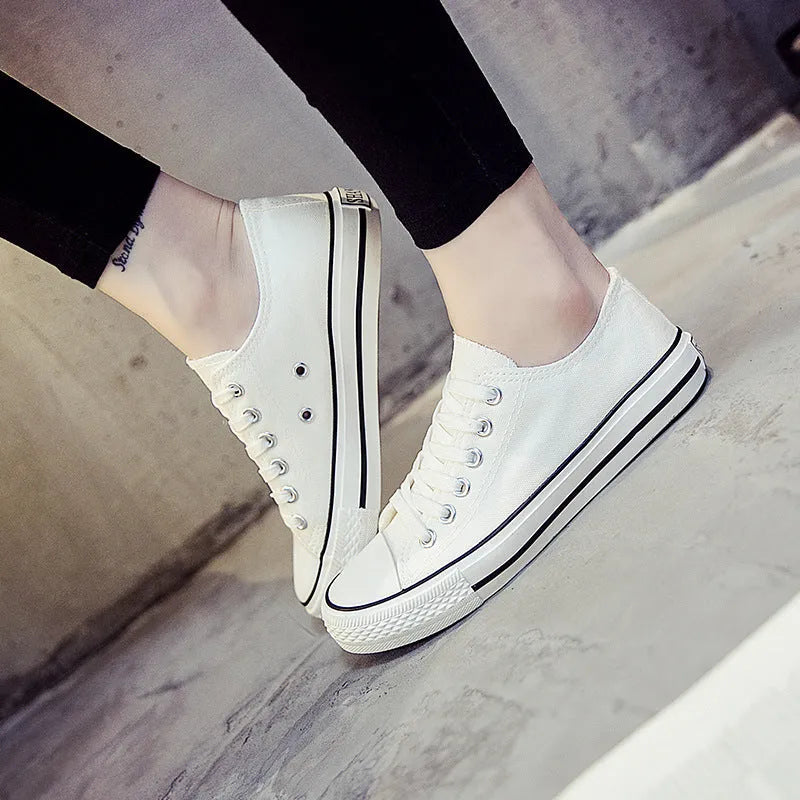 A pair of solid colour canvas lace-up trainers for women on a summer background.