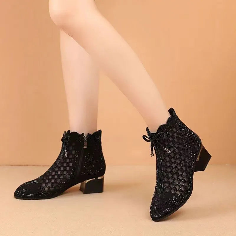 Black women's ankle boots with cutout mesh panels, mid heel, side zipper, and rhinestone sequin details