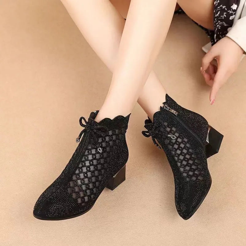 Black women's ankle boots with cutout mesh panels, mid heel, side zipper, and rhinestone sequin details