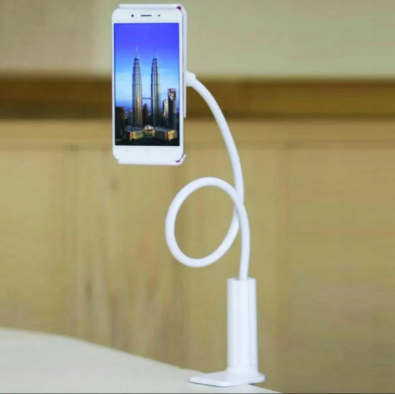 Black aluminium alloy bedside phone handset with a long arm and wide clamp, holding a mobile phone above a bed.