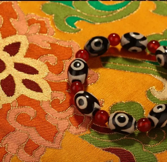 Three-eyed dzi bead bracelet with 10 barrel dzi beads and 6mm red agate beads, 6 inch