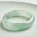 Light green jade bracelet on a wrist, showing its natural stone texture and colour.