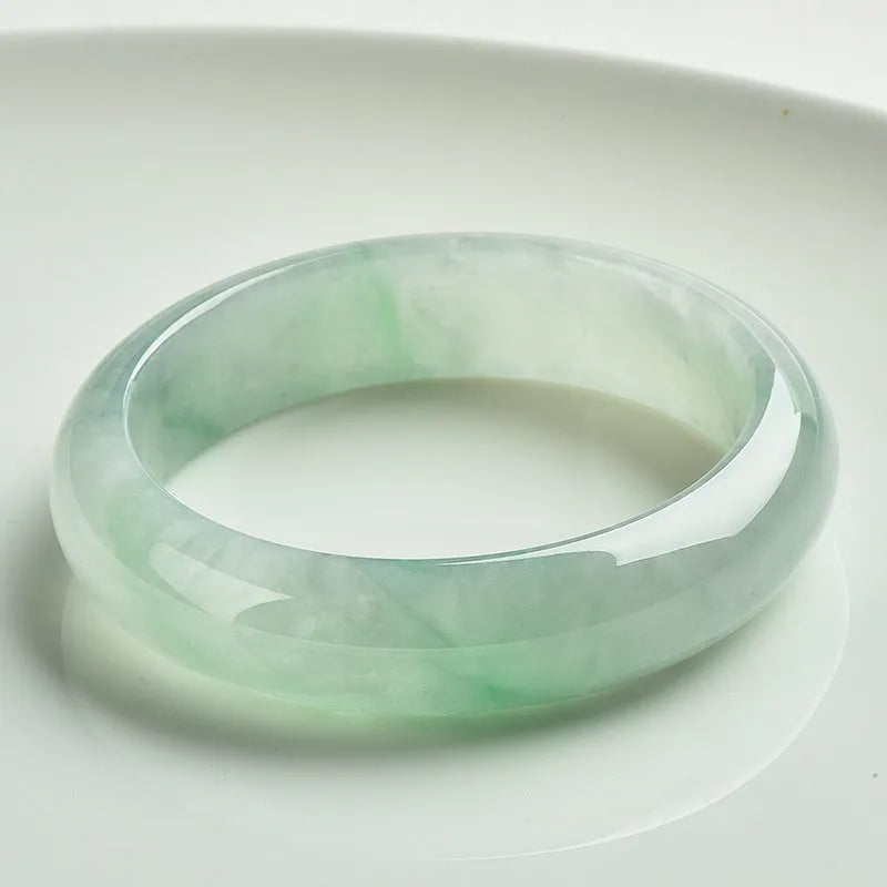 Light green jade bracelet on a wrist, showing its natural stone texture and colour.