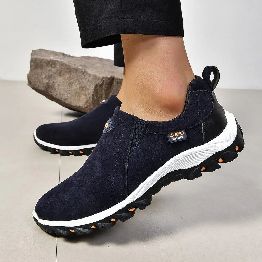 Men's grey slip-on shoe cover with round toe and rubber sole, shown from the side.