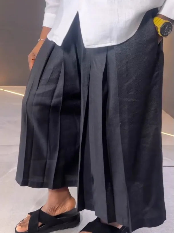 White asymmetrical shirt and black pleated trousers co-ordinate set laid flat