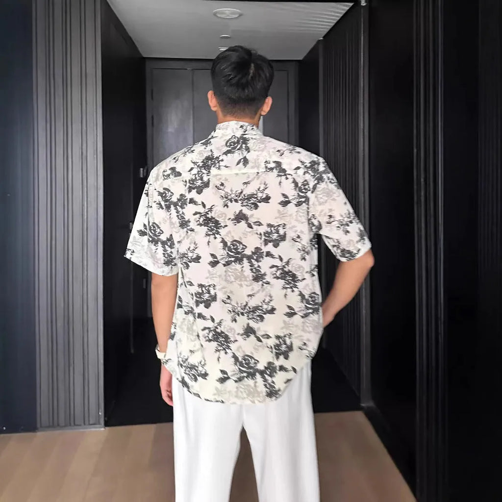 Loose-fitting black floral print short sleeve shirt on a hanger.