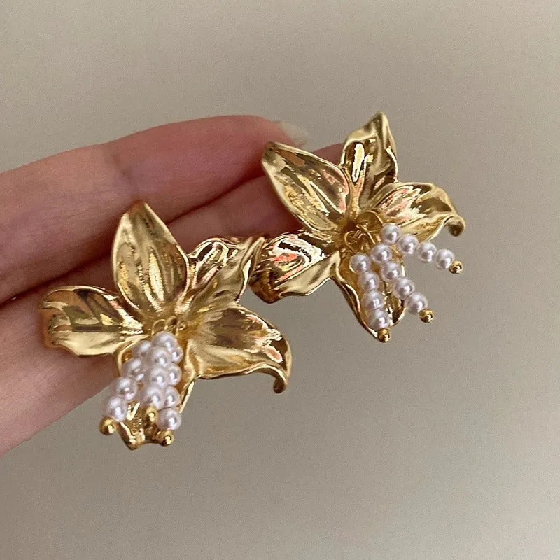 Gold H1795 metal flower earrings with an exaggerated floral design and pearl details.