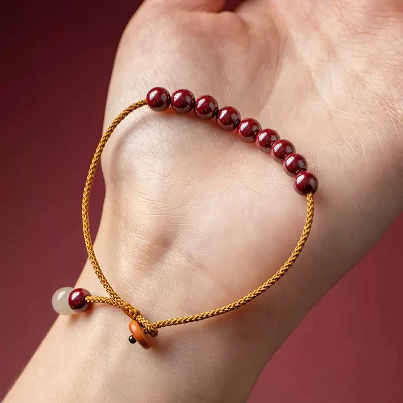 Hand-woven bracelet made of red cinnabar and raw Hetian Jade in a simple geometric shape.