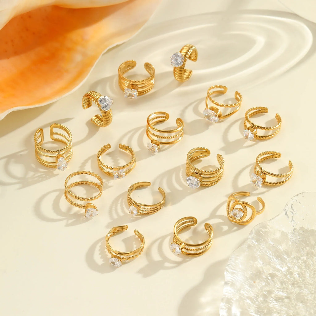 Geometric gold-coloured stainless steel ring with open mouth design on a plain background