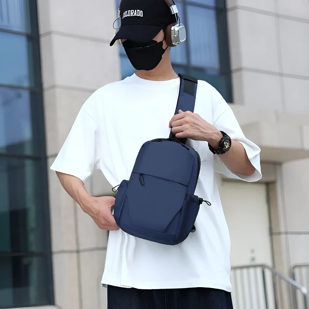 Grey men's chest bag worn across the shoulder, showing main compartment and waterproof-treated fabric.
